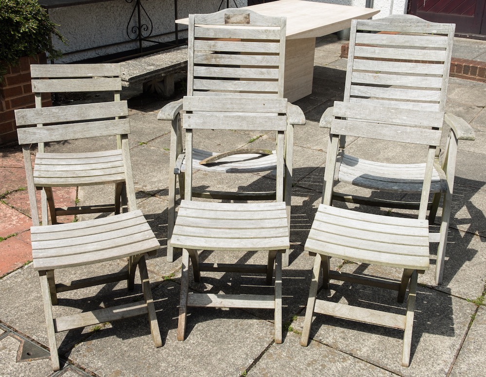 A pair of weathered teak adjustable garden armchairs and a set of four folding garden chairs:.