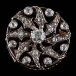 A gold backed silver and diamond mounted, circular brooch: the central round,