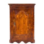 An early 18th Century walnut hanging corner cupboard:, with a moulded cornice and canted angles,