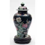 A Chinese famille noire baluster vase and cover with hardwood stand: painted with birds, prunus,