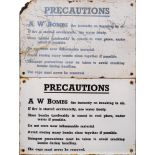 Two WWII enamel signs 'Precautions A W Bombs': black text on white ground, 20.5 x 30.