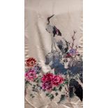 A Chinese embroidered silk panel: depicting two cranes perched on rockwork with flowering peonies
