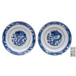 A pair of Chinese blue and white 'dragon' saucer dishes: each painted with a scaly dragon persuing