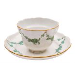 A Bristol tea bowl and saucer: of fluted ogee form, painted in green monochrome with floral swags,