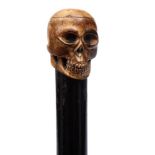 A 19th century marine ivory carved skull walking cane: mounted on an ebony shaft with marine ivory