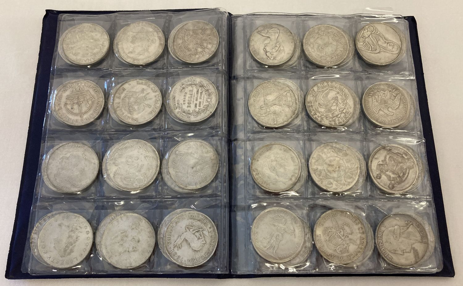 A folder containing 72 assorted white metal coins from around the world.