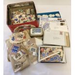 A tin of vintage used and unused British and world stamps and first day covers.