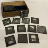 A vintage wooden box containing a quantity of glass negative photographic plates.