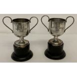 2 Chinese silver 1930's trophy cups, marked 'TAI HUA', on black painted wooden stands.