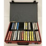 A red case containing a quantity of assorted vintage music audio cassettes.