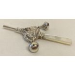 A white metal, pearl handled babies rattle with nursery rhyme detail.