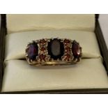 A vintage 9ct gold trilogy style garnet set gypsy ring.