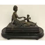 A filled bronze figure of a reclining semi naked classical female with cherub offering fruit.