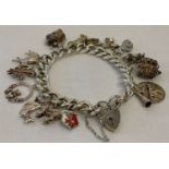 A vintage silver charm bracelet with padlock, safety chain and 16 silver and white metal charms.