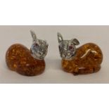 A pair of small faux amber rabbits, with white metal heads and red glass eyes.