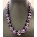 A graduating amethyst bead necklace with extension chain and silver clasp.