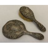 An Art Nouveau silver backed hand mirror with floral decoration and MBW engraved monogram.