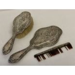 An Art Nouveau silver backed dressing table brush set with floral lily design decoration.
