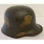 A German WWI style M16 stalhelm helmet with painted camouflage design, complete with leather liner.