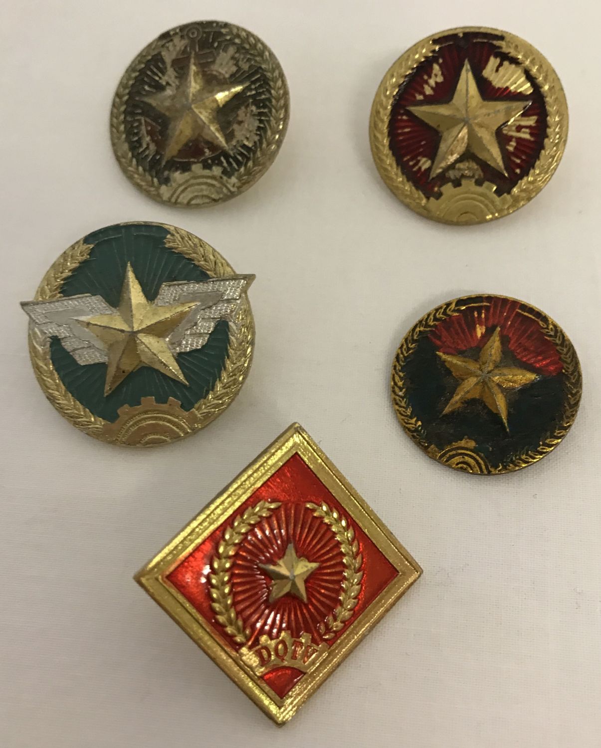 A group of 5 Vietnam War era Vietcong and N.V.A. metal helmet badges.