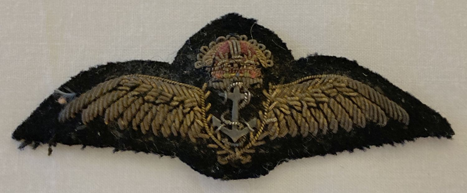 A vintage Royal Navy pilot qualification cloth wings badge with silver coloured metal anchor.