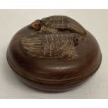 A small circular Japanese wooden lidded pot with carved turtle figures to lid.