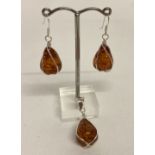 A silver set faux amber pendant together with a pair of matching earrings.
