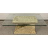A modern glass topped coffee table with stone effect base.