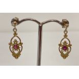A pair of 9ct gold classic design drop style earrings, each set with a small round cut ruby.