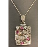 A decorative square shaped silver locket set with seed pearls, rubies and marcasite's.