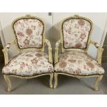 A pair of Louis XV style wooden framed armchairs, painted cream.
