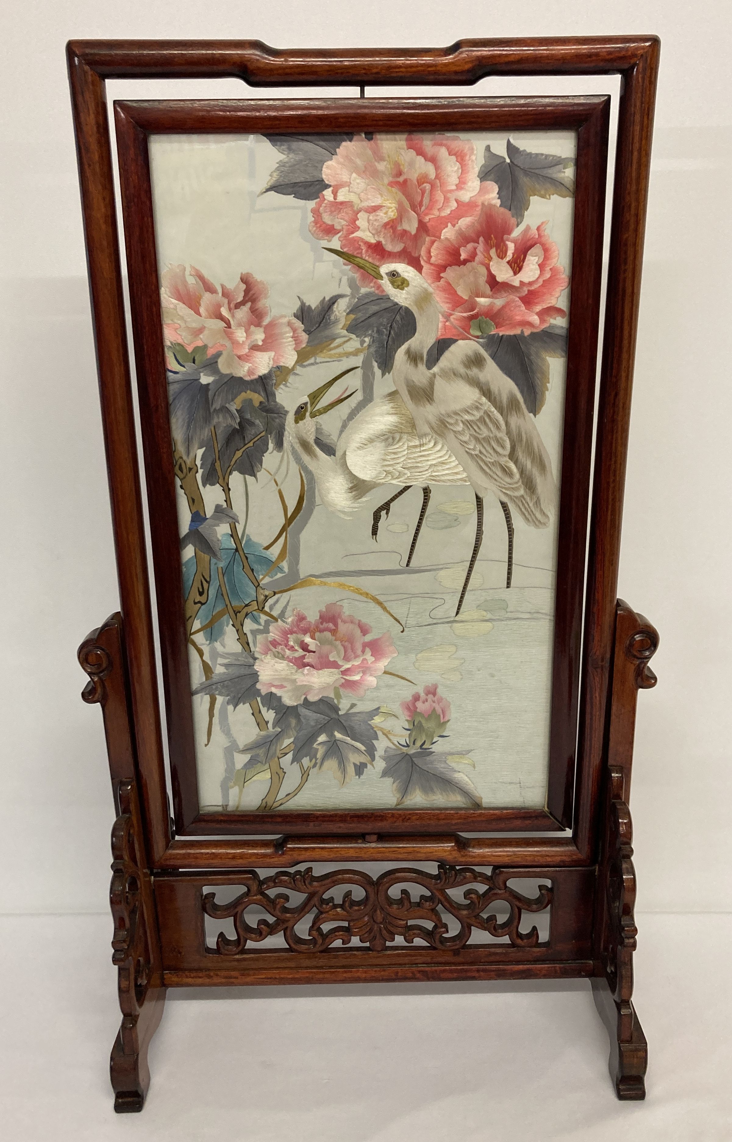 A modern wooden framed Oriental swivel screen with embroidered silk panel, behind glass.