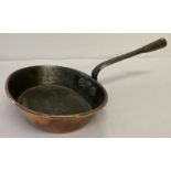 An antique copper small oval shaped frying pan with riveted handle.