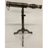 A small brass telescope mounted on an extending tripod base with folding feet.