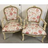 A pair of Louis XV style wooden framed armchairs, painted cream.