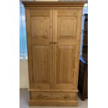 A modern solid wood pine double wardrobe with lower drawer and fixed plinth top.