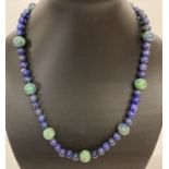 An 18" lapis lazuli and azurite beaded necklace with white metal S shaped clasp.