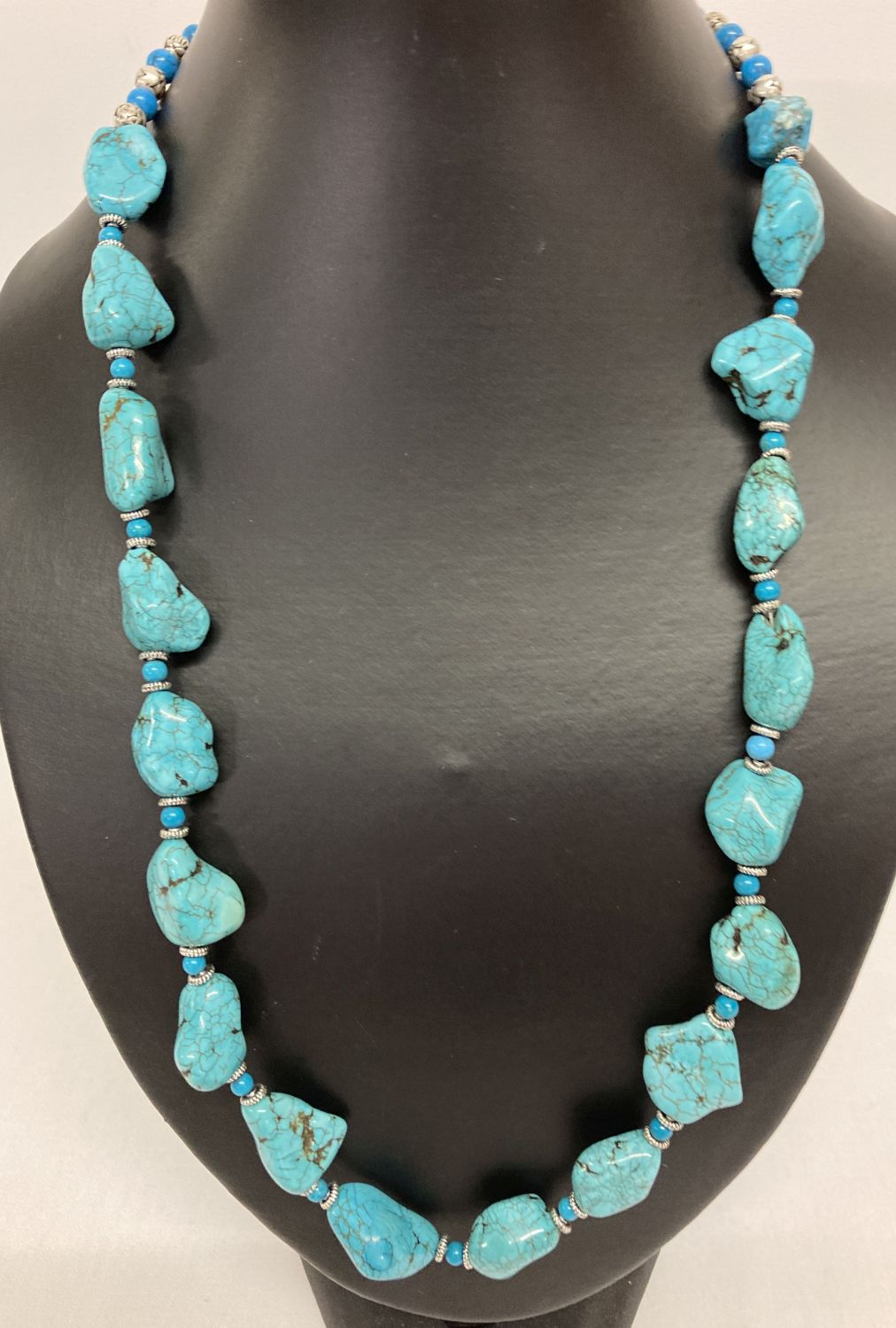 A 24" turquoise and white metal beaded necklace with S shaped clasp.