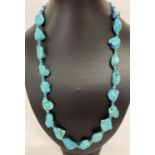A 24" turquoise and white metal beaded necklace with S shaped clasp.