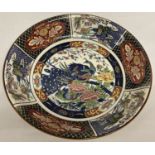A large oriental charger with panel decoration and central peacock detail. Repair to rim.