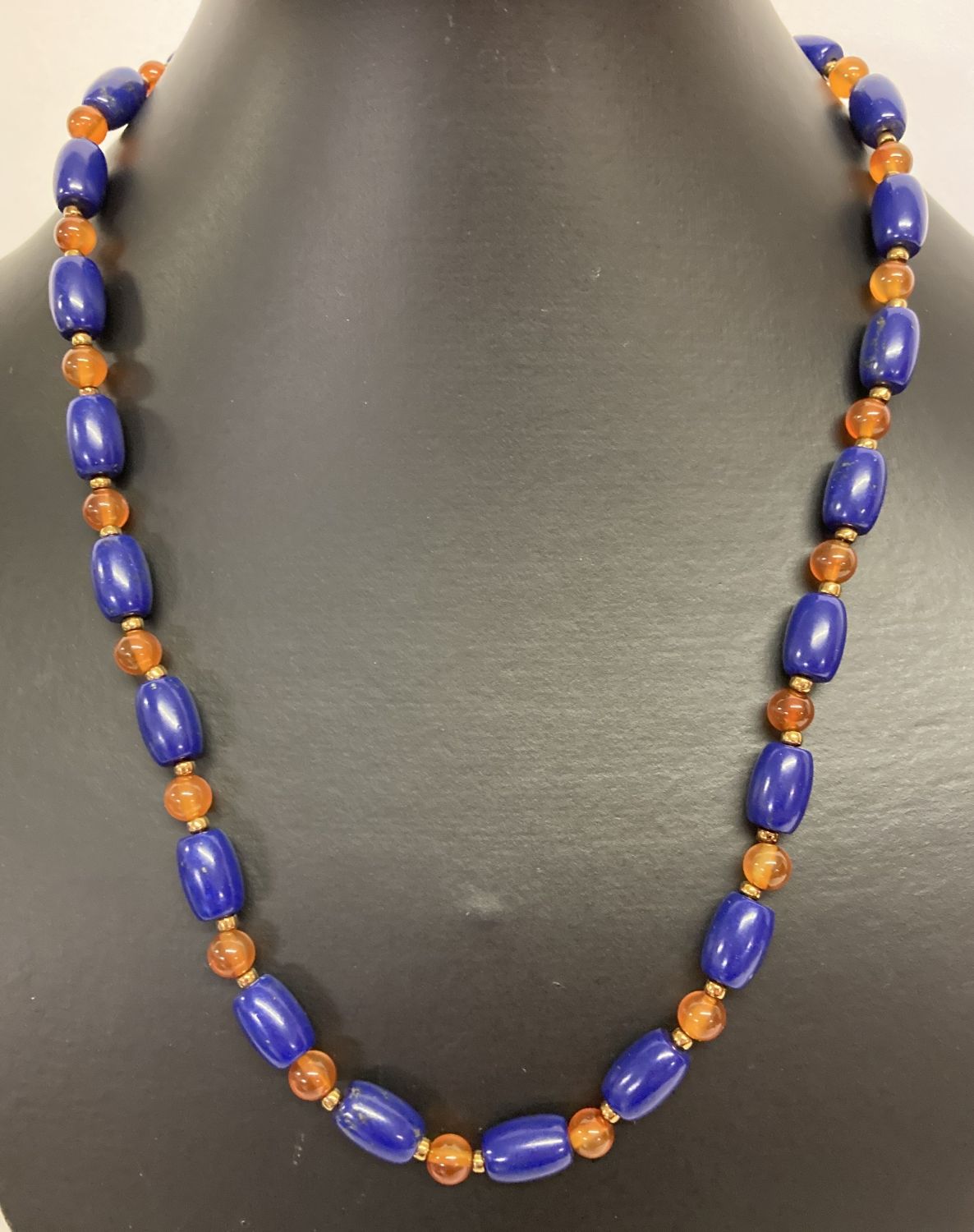 A 19" blue stone and carnelian beaded necklace with gold tone T bar clasp.