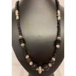 A 29" costume jewellery necklace with black horn, wood, cinnabar and white metal beads.