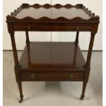 A small dark wood occasional trolley with shaped galleried top, 2 drawers and brass caster feet.