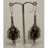 A large pair of 925 silver drop earrings set with red tear drop shaped stones.