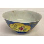 A Chinese tea bowl with blue glaze to outer bowl and yellow panel detail depicting floral designs.