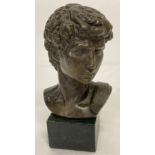 A small bronze bust of David set on a square shaped marble base.