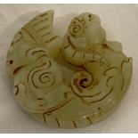A Chinese Jade roundel depicting figural detail to one end and mythical creature to the other.