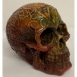 A large carved multi coloured resin, amber style skull figurine decorated with Pagan style symbols.