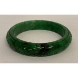 A Chinese green apple jade bangle with engraved detail.