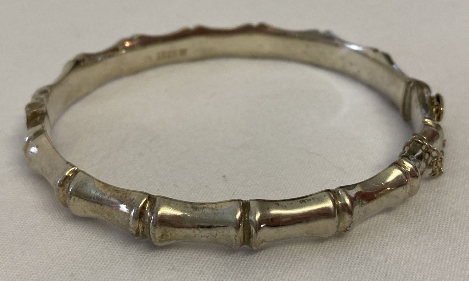 A vintage bamboo design silver bangle with safety chain. Hallmarked Birmingham 1966.